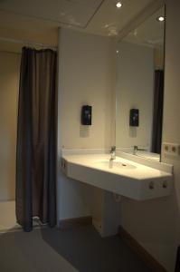a bathroom with a sink and a mirror at HI Hostel Dunepanne in De Haan