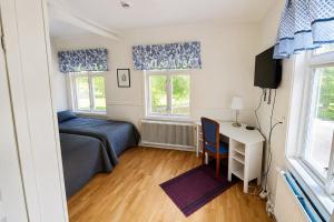 a bedroom with a bed and a desk and windows at Husby Wärdshus in Dala Husby