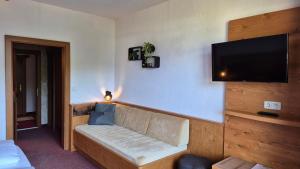 a living room with a couch and a flat screen tv at Hotel Dahoam by Miha in Westendorf