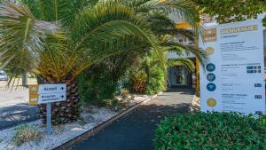 a palm tree in front of a building with a sign at Premiere Classe Biarritz in Biarritz