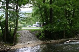 an rv parked next to a river with trees at Avtokamp pri mlinu - Tent or Camper Pitch - Dujčeva domačija in Vremski Britof