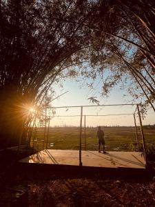 a man standing on a swing with the sun in the background at Laena Homestay in Ko Yao Noi