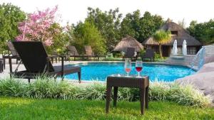 two glasses of wine on a table next to a pool at Radiant Resort in Manzini