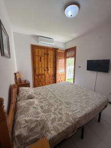 a large bed in a bedroom with a television at Casa en la playa con piscinas in Gran Alacant