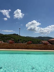 a swimming pool with blue water in front of a wall at Chianti Borgo 28 in Gaiole in Chianti