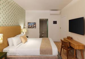 a bedroom with a bed and a desk and a television at Leonardo Kolymbia Resort Rhodes in Kolymbia