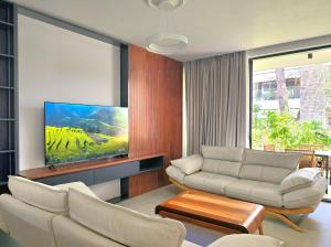 a living room with two white couches and a flat screen tv at Seaside Premium Villa in Lalzit Bay