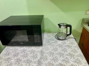 a microwave sitting on a counter next to a blender at Ava s Cozy Studio in Tunbridge
