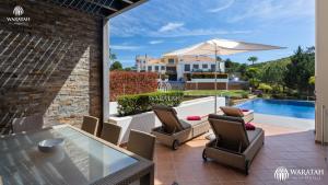 a patio with a glass table and chairs and an umbrella at Emily in Vale do Lobo