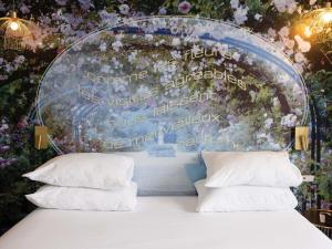a bed with pillows in front of a wall with flowers at Hôtel Mercure Paris Suresnes Longchamp in Suresnes +89 photos