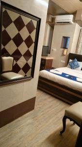 a bedroom with a mirror and a bed and a chair at Hotel Oliver in Mumbai +3 photos