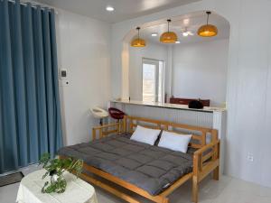 a bedroom with a bed with blue curtains and a table at SAN HÔ Beach Homestay in Thôn Ðông Giang