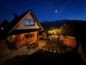 a log cabin at night with the moon in the sky at Domek Pod Wierchami z Jacuzzi in Kościelisko +134 photos