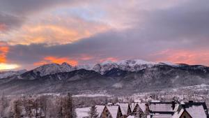 a snowy mountain range with houses and snow covered mountains at Domek Pod Wierchami z Jacuzzi in Kościelisko