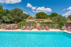 a villa with a swimming pool and pink chairs at Gite les Mazets du Rouret in Saint-Christol-lès-Alès