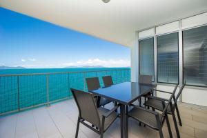 a table and chairs on a balcony with a view of the water at 1 Bright Point Apartment 5301 in Nelly Bay