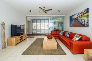 a living room with a red couch and a tv at 1 Bright Point Apartment 5301 in Nelly Bay +9 photos