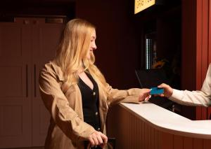 a woman standing at a counter holding a credit card at The Address Wren in Glasgow