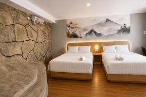 a hotel room with two beds and a rock wall at Samara Villa by Sinergi in Tawangmangu