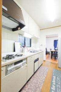 a kitchen with white cabinets and a stove top oven at お宿 しんみち in Nagoya