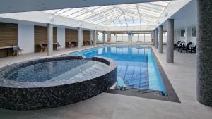a pool in a building with a large tub at Widdy Bay View in Widemouth Bay