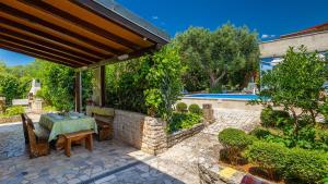 a patio with a table and chairs and a pool at Villa Rossy by Villas Guide in Pavicini