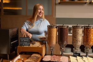 a woman standing in a kitchen with some food at The Address Wren in Glasgow
