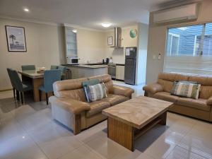 a living room with couches and a table and a kitchen at Unit 66 Seafront Estate in Jurien Bay