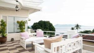 a porch with white chairs and a table on a balcony at Casa Bahia Dive Resort in Mabini