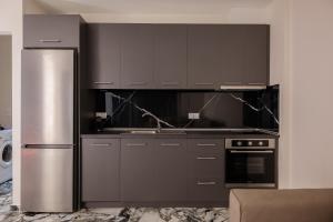 a kitchen with black cabinets and a stainless steel refrigerator at Sweet Suites in Nea Peramos +16 photos