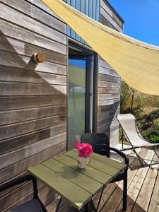 a picnic table with a vase of flowers on a patio at Chambre privée proche plages in Plozévet