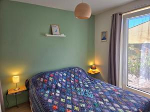 a bedroom with a bed with a quilt on it at Chambre privée proche plages in Plozévet
