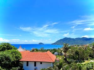 a house with a red roof with the ocean in the background at Viking House Apartment in Ko Tao
