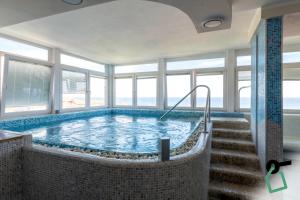 a large swimming pool in a building with windows at HOTIDAY Room Collection - Alassio Centro in Alassio