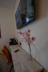 Eine Vase mit rosa Blumen auf einem Holztisch in der Unterkunft Hotel het Dok in IJmuiden