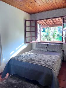 a bedroom with a bed with a window in it at Chalé Lumiar M&C in Lumiar