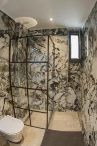 a bathroom with a toilet and a stone wall at Sweet Suites in Nea Peramos