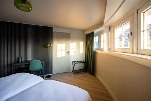 a bedroom with a bed and a desk and windows at Stadshotel Tante Annie's in Oldenzaal