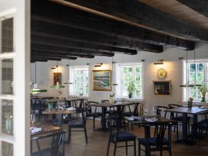 a dining room with tables and chairs and windows at Nørby Boutique Hotel in Fanø