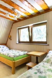 a room with two beds and a table and two windows at Chata u lesa in Prostřední Bečva