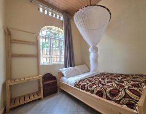 a bedroom with a bed and a window at Akagera Sunset House in Kabarondo