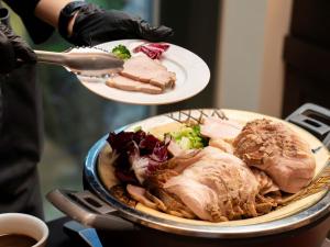 a person holding a plate of food on a table at Hotel Resol Trinity Naha in Naha