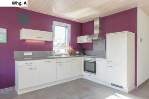 a kitchen with white cabinets and a purple wall at Ferienwohnung Philip in Meersburg