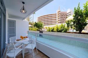 a balcony with a table and chairs and a swimming pool at Fayna Apartments in Playa del Ingles
