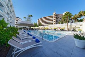 a row of lounge chairs next to a swimming pool at Fayna Apartments in Playa del Ingles
