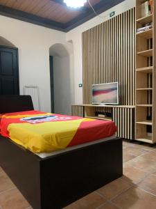 a bedroom with a bed and a tv on a shelf at Casa Mao in Noto