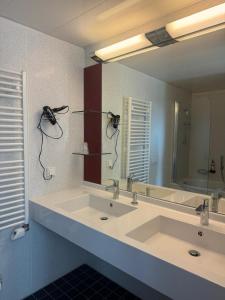a bathroom with two sinks and a large mirror at Hotel Regina Suites in Sankt Augustin