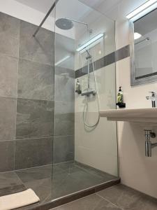 a glass shower in a bathroom with a sink at Hotel Regina Suites in Sankt Augustin