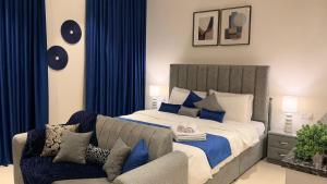 a bedroom with a bed with a couch and blue curtains at Navy Studio By Bait Zain in As Sīfah +21 photos