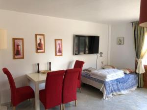 a bedroom with a bed and a table and red chairs at Veracoast 133 in Los Amarguillos